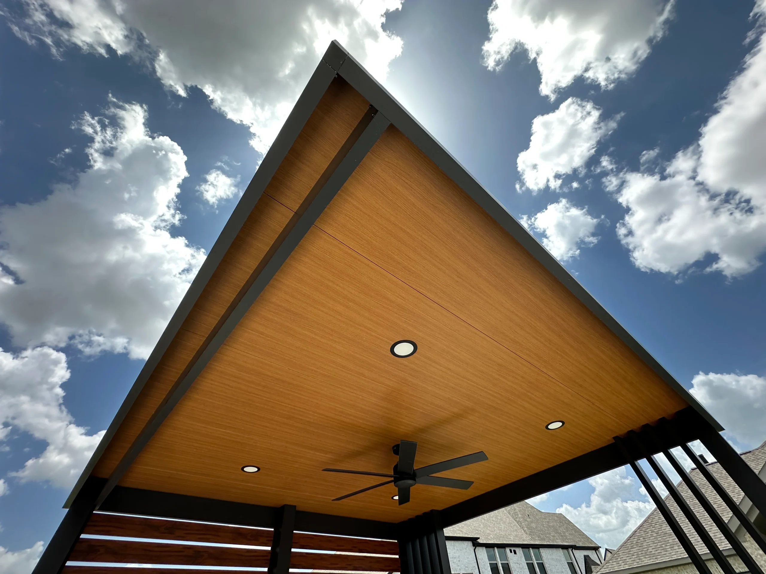 Slanted cantilever pavilion with natural oak ceiling and bronze framing