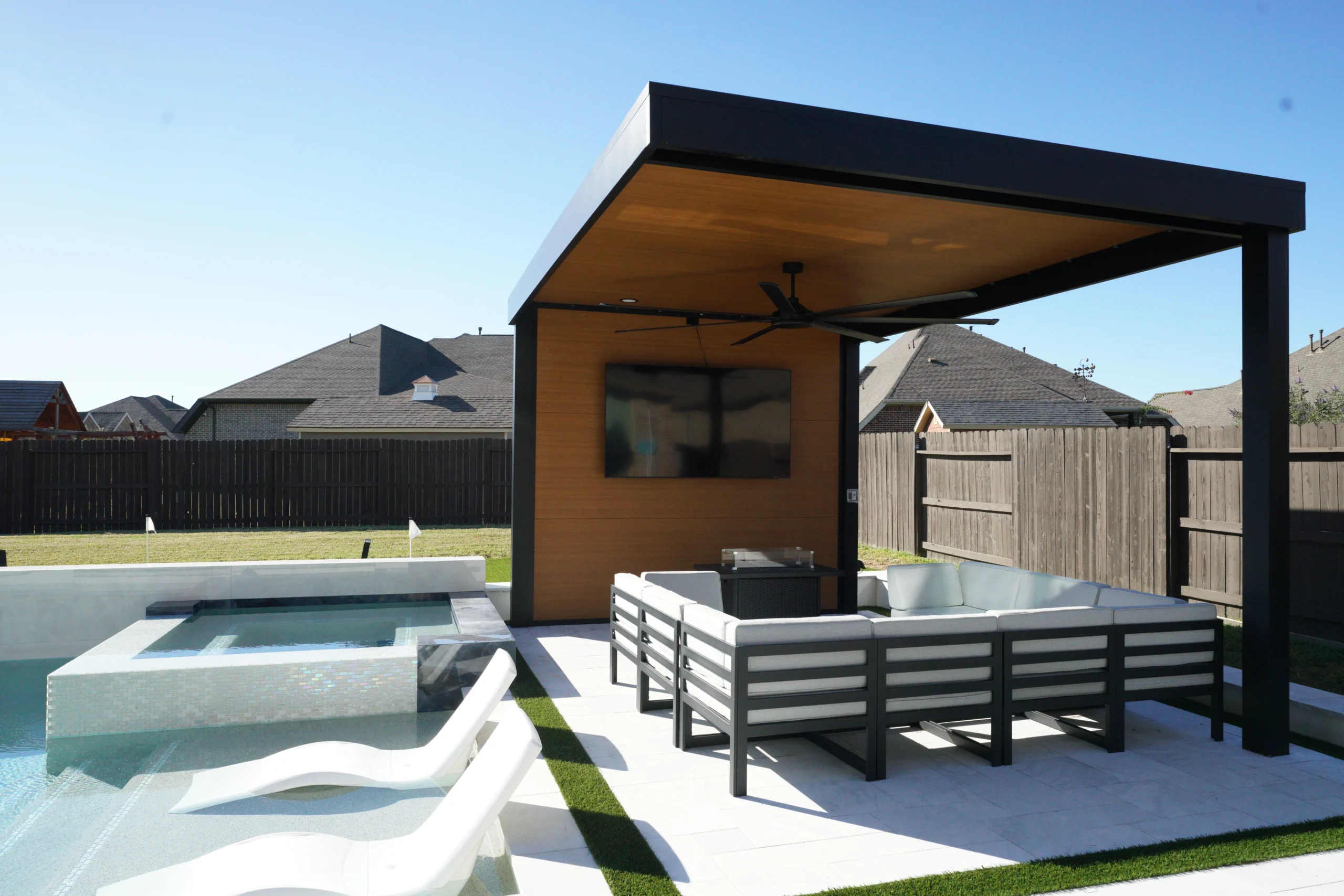 Cantilevered aluminum shade structure with wood ceiling beside a pool and lounge seating