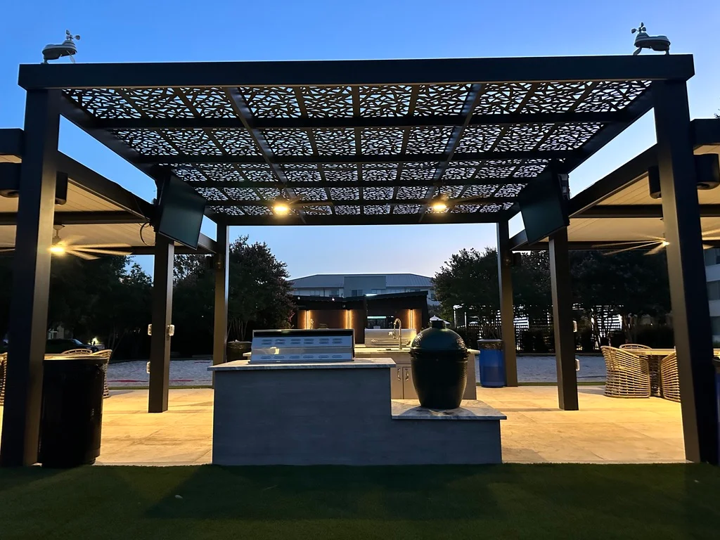 Patterned metal pergola over an outdoor kitchen at twilight