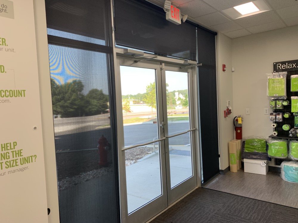 Commercial glass entry with a dark interior roller shade half down