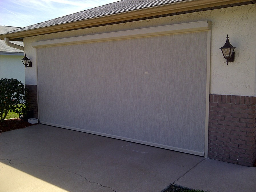 Garage opening fitted with a large cream motorized retractable screen