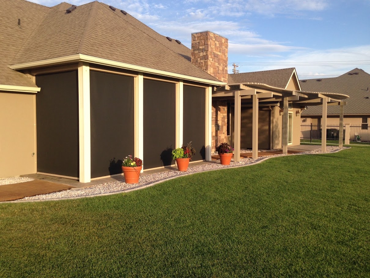 Stucco home at golden hour with three black retractable screens down along a side patio