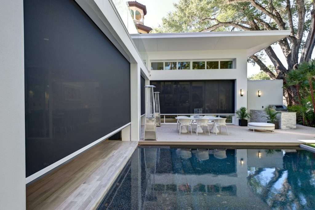 Modern poolside patio with large black motorized solar screens