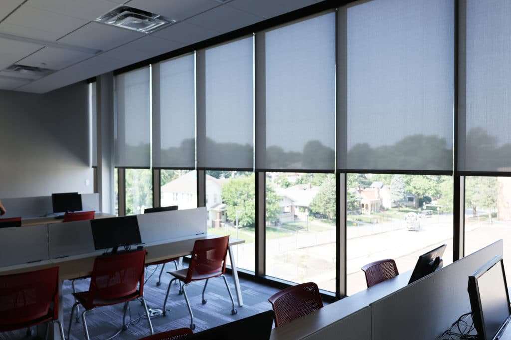 Commercial interior with a bank of roller shades across a glass facade